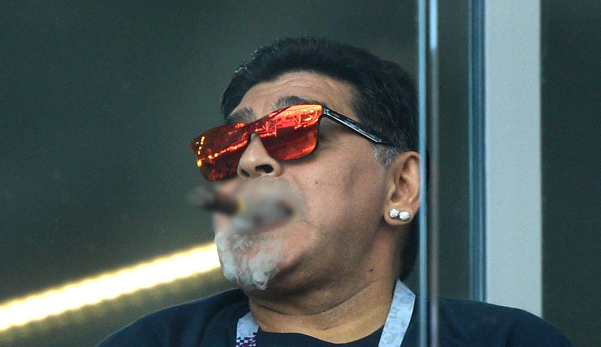 Mantan bintang sepak bola, Diego Maradona merokok saat menyaksikan laga antara Argentina dan Islandia dalam penyisihan Grup D Piala Dunia 2018 di Stadion Spartak, Moskow, Rusia, Sabtu (16/6). (Juan Mabromata/AFP)