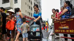 Warga membawa wadah berisi air usai mengisinya dari truk tangki pasokan pemerintah di Hanoi, Vietnam, Kamis (17/10/2019). Warga Hanoi melaporkan bahwa air ledeng yang mereka gunakan bau plastik terbakar. (Nhac NGUYEN/AFP)