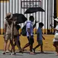 Turis dengan kipas angin dan payung mengunjungi museum arena adu banteng Real Maestranza selama gelombang panas di Seville pada 10 Juli 2023. (AFP/Cristina Quicler)