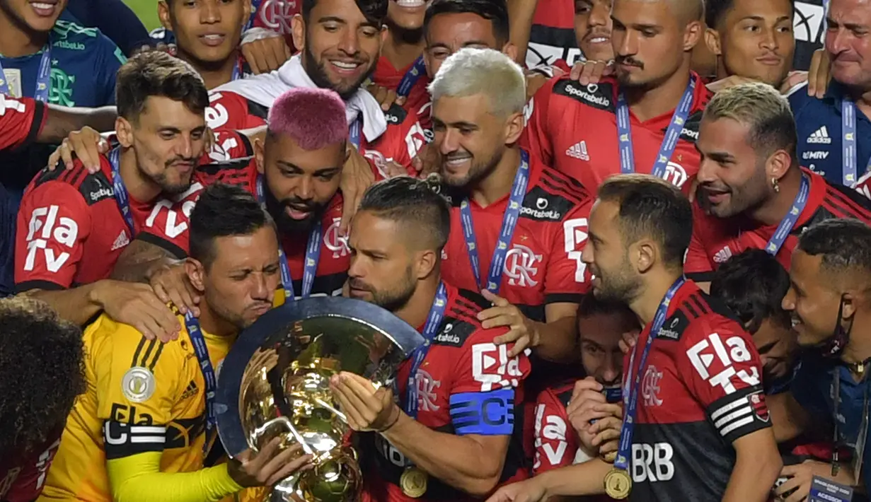 Kapten tim Flamengo Diego (kiri) mencium trofi disaksikan rekan satu timnya usai menjuarai Liga Brasil di Sao Paulo, Kamis (25/2/2021). (Foto: AFP/Nelson Almeida)