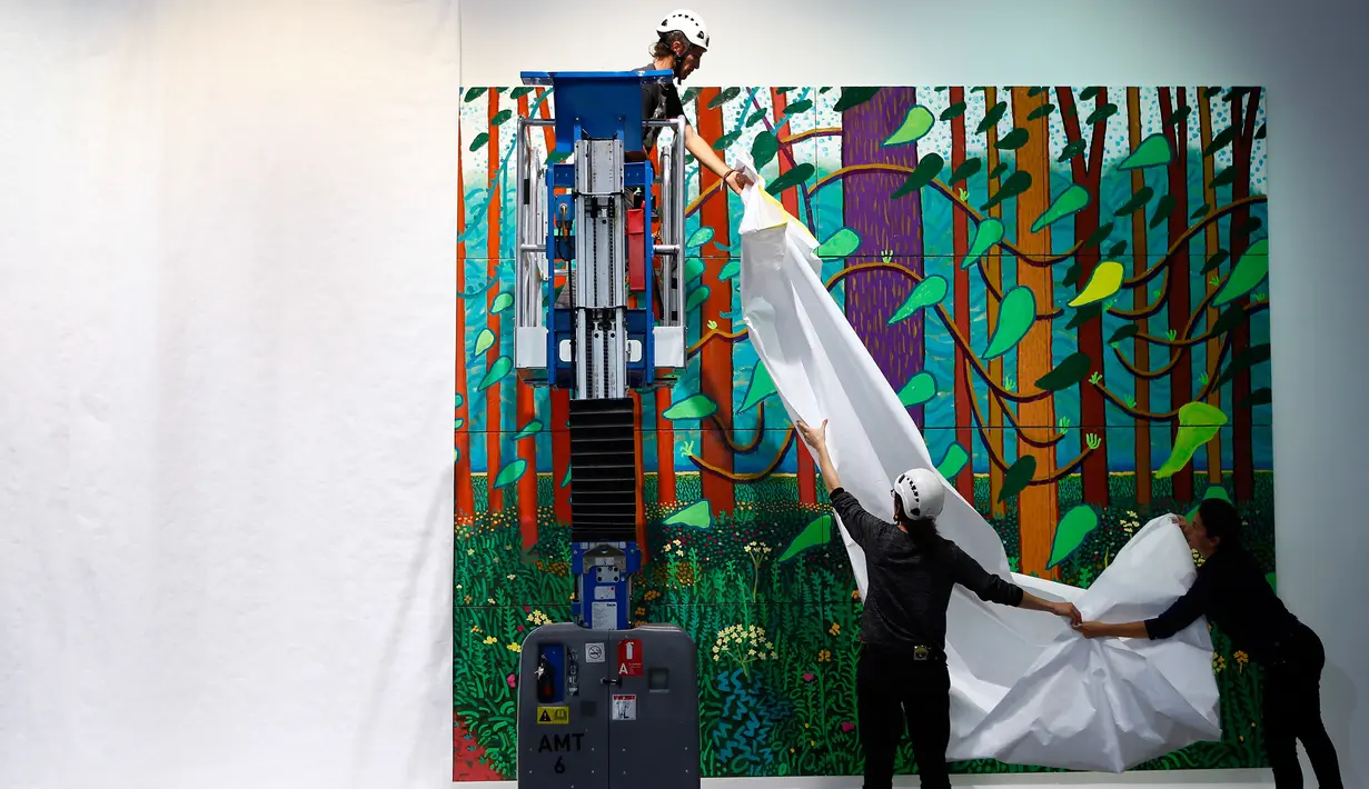 Para petugas membuka kain yang melindungi lukisan karya David Hockney di Perpustakaan Pompidou Center, Paris, Perancis, Selasa (26/9). Lukisan tersebut menjadi bagian dari retrospektif perjalanan karya pria berusia 80 tahun ini. (Foto AP/Francois Mori)