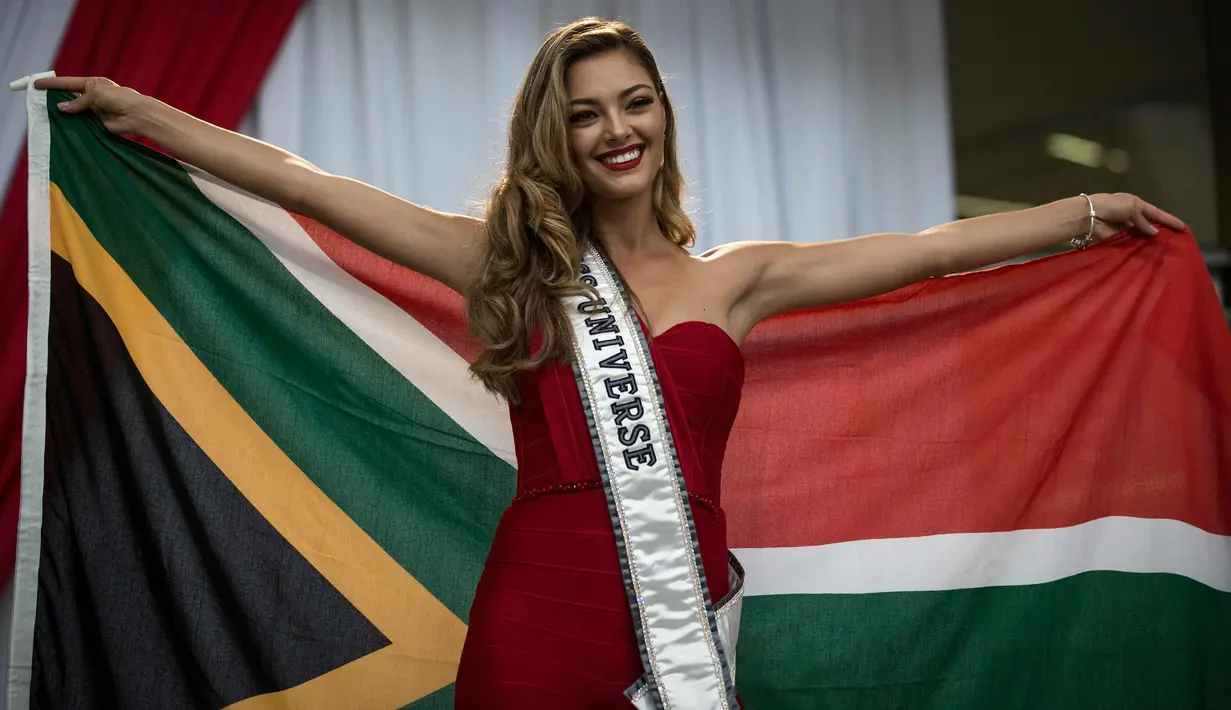 Miss Universe 2017 Demi-Leigh Nel-Peters berpose dengan bendera Afrika Selatan saat tiba di Bandara Internasional OR Tambo di Johannesburg (24/1). Untuk pertama kalinya setelah dinobatkan Demi Leigh baru pulang ke Afrika Selatan. (AFP Photo/Gulshan Khan)