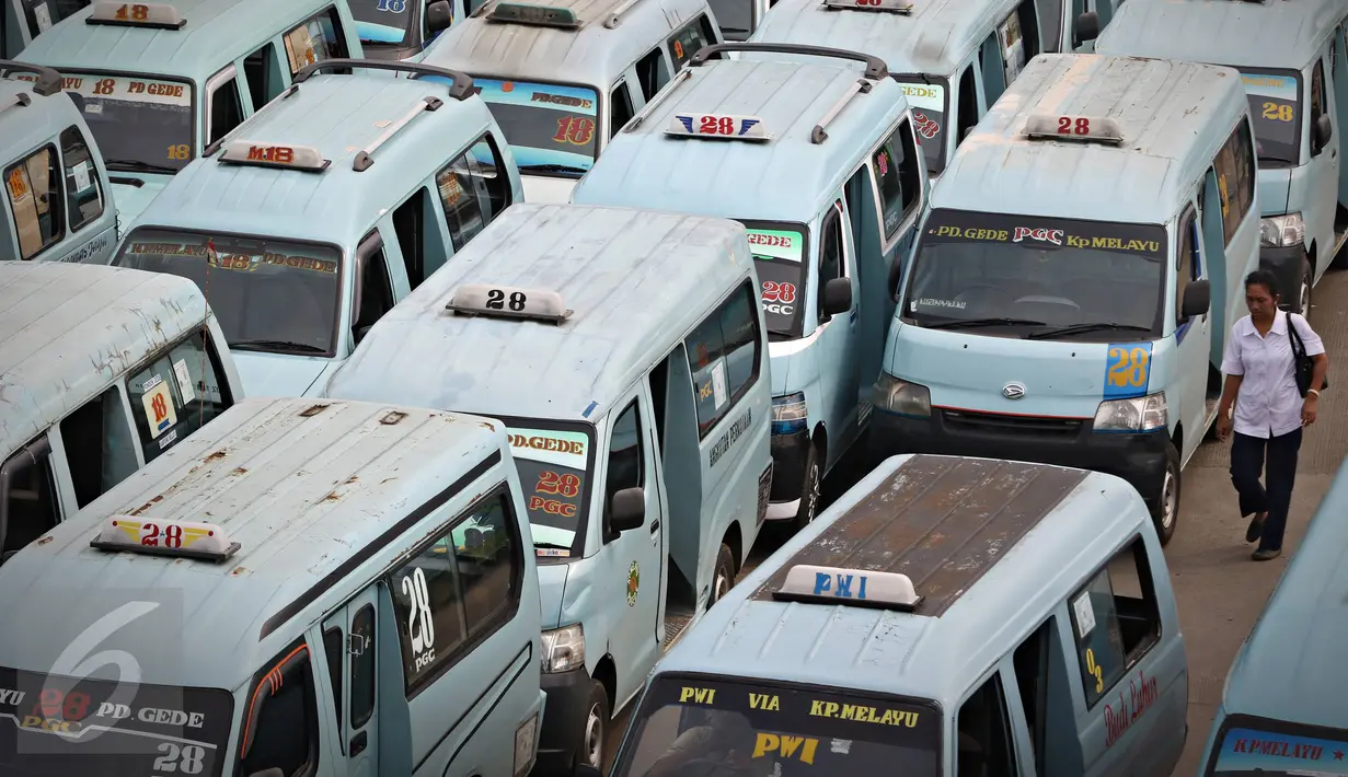 Warga berjalan di dekat antrean mikrolet yang menunggu penumpang di Terminal Kampung Melayu, Jakarta, Selasa (17/11). Dinas Perhubungan DKI menunda penerapan sanksi bagi angkutan umum yang tidak menutup pintu saat berjalan (Liputan6.com/Immanuel Antonius)
