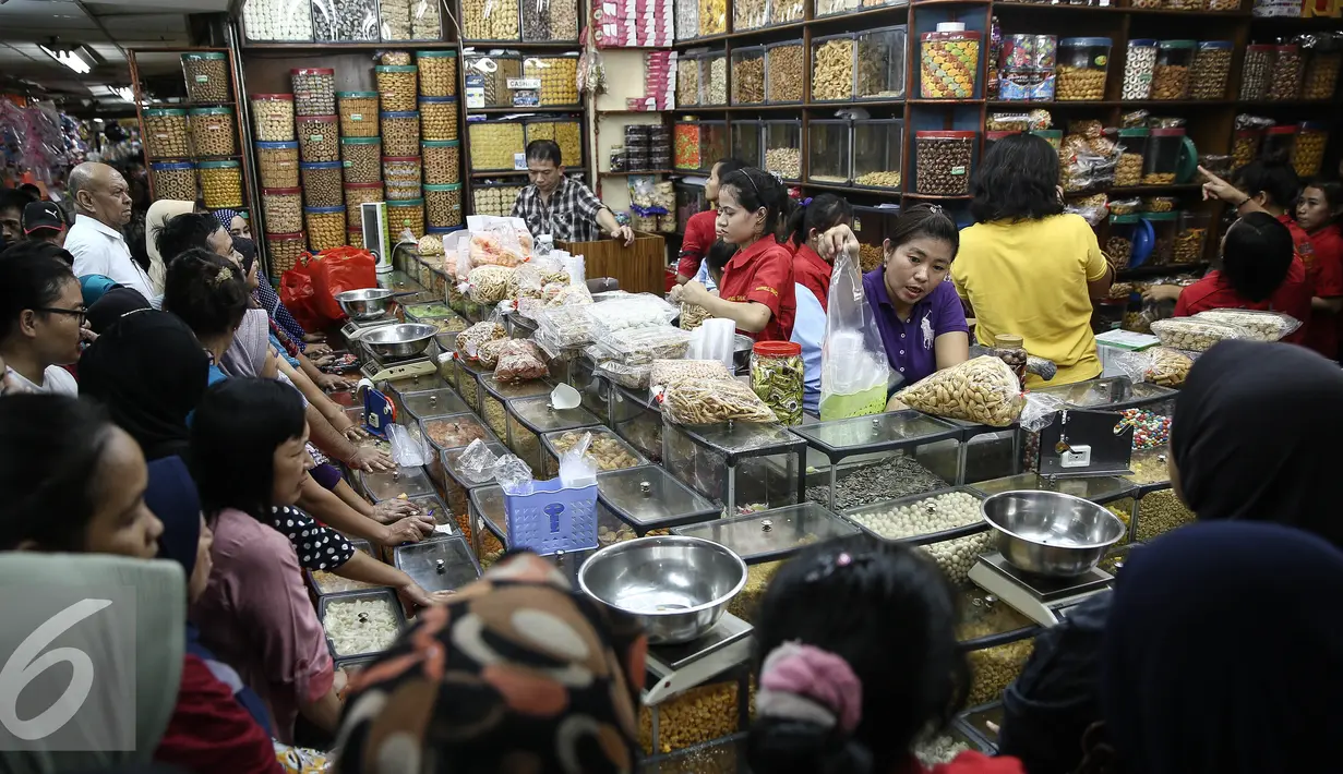 Sejumlah calon pembeli mengantre membeli kue kering di Pasar Jatinegara, Jakarta, Senin (27/6). Alasan warga membeli panganan khas lebaran di toko kue karena lebih praktis dan terjangkau harganya. (Liputan6.com/Faizal Fanani)