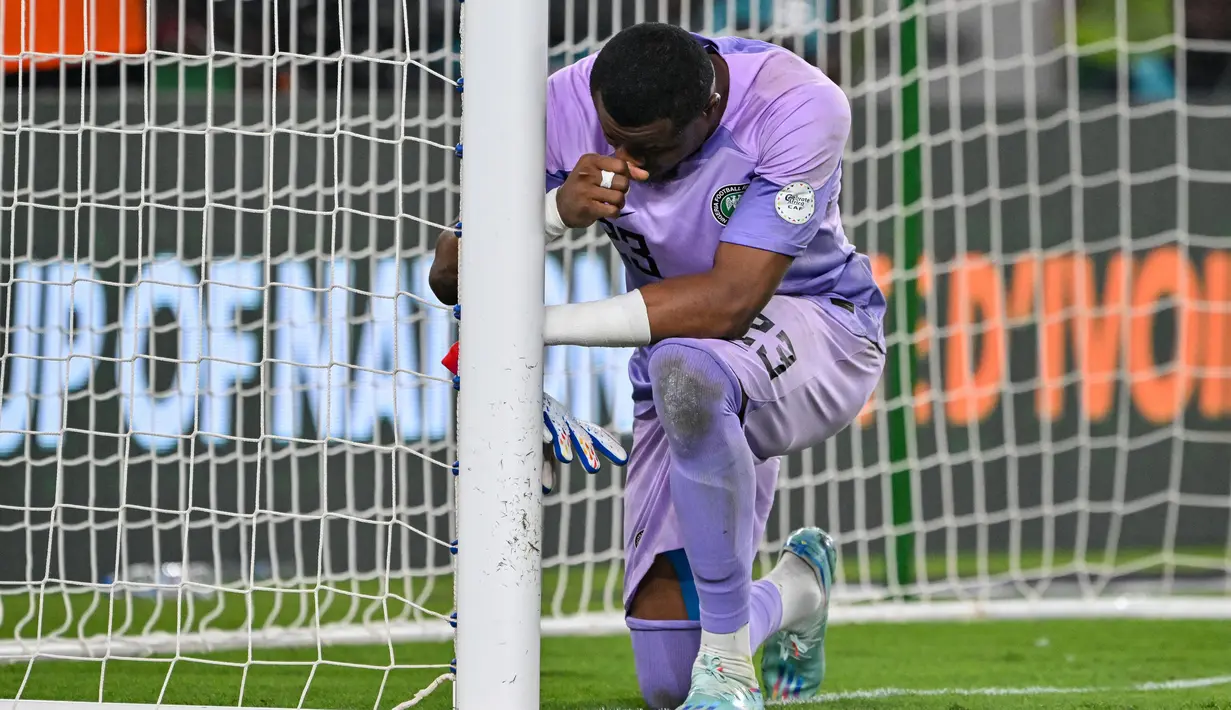Kiper Nigeria, Stanley Nwabali, terharu saat berhasil menghalau bola tendangan penalti pemain Afrika Selatan pada laga semifinal di Stade de la Paix, Kamis (8/2/2024). (AFP/Issouf Sanogo)