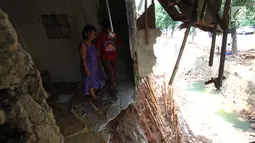 Warga mengamati bagian belakang rumahnya rusak akibat terkena longsor di pinggir kali Bintaro Utara, Pesanggrahan, Jakarta, Kamis (20/9). Hujan lebat mengakibatkan sebanyak lima rumah di pinggir kali tersebut longsor. (Liputan6.com/Angga Yuniar)