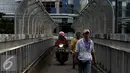 Pejalan kaki dan pemotor melintas di atas JPO di kawasan Grogol, Jakarta, Rabu (4/5). JPO yang seharusnya diperuntukkan bagi pejalan kaki itu kini sering dimanfaatkan pengendara motor untuk jalan pintas. (Liputan6.com/Gempur M Surya)