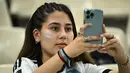 Seorang fans wanita Argentina menggunakan ponselnya di tribun jelang pertandingan semifinal Piala Dunia Qatar 2022 antara Argentina dan Kroasia di Stadion Lusail di Lusail, utara Doha, Rabu (14/12/2022). (AFP/Jewel Samad)