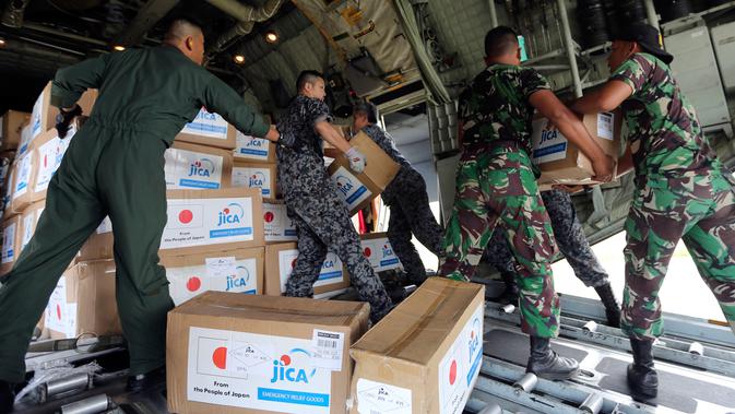 Personil militer Jepang dibantu TNI mengangkut bantuan logistik dari pesawat kargo AU Jepang di bandara Mutiara Sis Al-Jufri, Palu, Sulteng (6/10). Gempa berkekuatan 7,5 mengguncang kota Palu pada 28 September. (AP Photo/Tatan Syuflana)