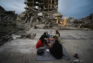 Bagi banyak warga di Gaza, Ramadan tahun ini dijalani dalam kondisi yang jauh lebih sulit. Banyak keluarga kehilangan tempat tinggal akibat serangan udara yang merusak rumah-rumah dan infrastruktur sipil. Tampak dalam foto, anggota keluarga Al-Najar berbuka puasa selama bulan suci Ramadan di tengah reruntuhan bangunan yang hancur di Kota Gaza, Jumat 13 Maret 2026. (AP Photo/Jehad Alshrafi)