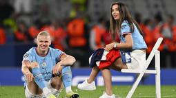 Pemain Manchester City, Erling Haaland, bersantai dengan kekasihnya Isabel Haugseng Johansen saat perayaan gelar juara Liga Champions di Ataturk Olympic Stadium, Istanbul, Minggu (11/6/2023). Erling Haaland tampil luar biasa dan mampu meraih treble winner di musim perdananya bersama City. (AFP/Paul Ellis)