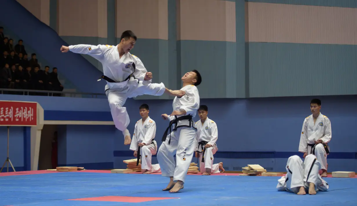 Peserta melakukan tendangan saat berusaha mengalahkan lawannya selama demonstrasi taekwondo sebagai bagian dari Kejuaraan Seni Bela Diri Nasional tahunan Mangyongdae di 'Taekwon-Do Hall' di Pyongyang, Korea Utara (9/11). (AFP Photo/Kim Won Jin)