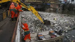 Pekerja kota membuang sampah yang mengapung di Sungai Negro, yang permukaan airnya naik karena hujan, di Manaus, negara bagian Amazonas, Brasil, Senin (6/6/2022). Sekitar 35 ton sampah dikeluarkan setiap hari dari air di Manaus, menurut ke Kota. (AP Photo/Edmar Barros)