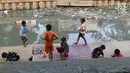 Anak-anak bermain di bantaran anak Sungai Ciliwung, Jakarta, Rabu (6/6). Meskipun tidak layak sebagai tempat bermain, namun lokasi itu menjadi tempat bagi anak-anak di kawasan tersebut untuk menunggu waktu berbuka. (Liputan6.com/Immanuel Antonius)