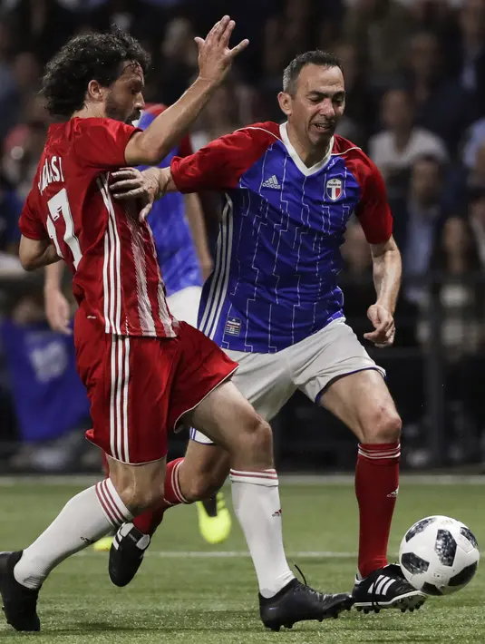 Gelandang Youri Djorkaeff membawa dari kawalan Damiano Tommasi saat pertandingan tim Prancis 98 dengan tim FIFA 98 di Arena U, Nanterre, Paris (12/6). Pertandingan ini memperingati 20 tahun kemenangan Prancis di Piala Dunia 1998. (AFP Photo/Thomas Samson)