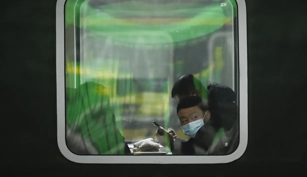Seorang pria melihat keluar jendela di kereta api di stasiun kereta api Beijing di ibu kota China (7/1/2023). Ketika migrasi tahunan dimulai dengan orang-orang yang kembali ke kampung halaman mereka untuk perayaan Tahun Baru Imlek. (AFP/Wang Zhao)