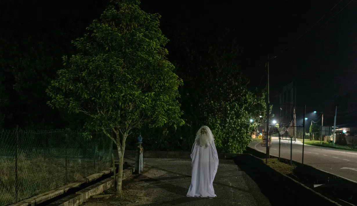Urabil Alias, 38, mengenakan kostum hantu saat berjalan di daerah perumahan selama aturan pembatasan gerakan atau Movement Control Order di Terengganu, Malaysia, 16 April 2020. Aksi pria itu untuk menakuti warga agar tidak keluar dari rumah selama lockdown akibat virus corona. (Mohd RASFAN/AFP)