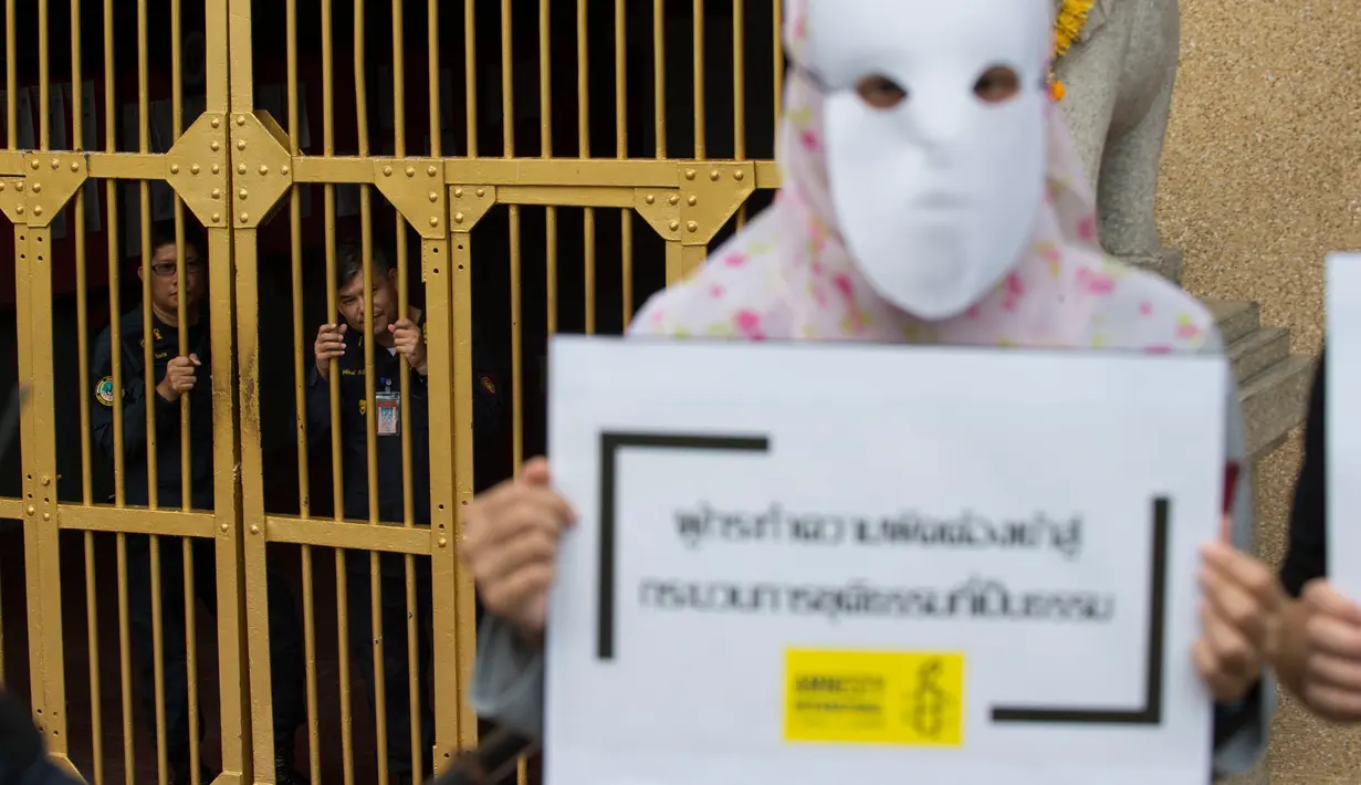 Penjaga menonton aktivis Amnesty International melakukan aksi tolak hukuman mati dengan suntik di depan penjara Bang Kwang di Nonthaburi, Bangkok (19/6). Mereka mengutuk hukuman mati terhadap Theerasak Longji pada 18 Juni 2018. (AFP PHOTO / Romeo Gacad)