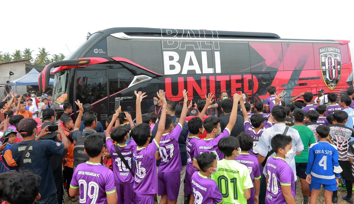 Sejumlah pemain SSB melambaikan tangan ke arah bus yang berisi pemain Bali United usai acara penyerahan bola ke 70 SSB se-bali. (Bola.com/ M Iqbal Ichsan)