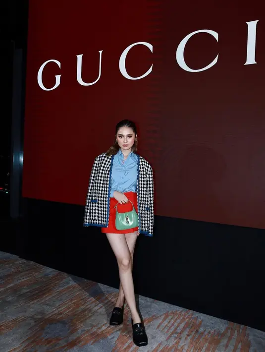 Syifa Hadju menghadiri acara Gucci mengenakan one brand outfit semuanya dari Gucci. Tampil cantik bak boneka Barbie, Syifa Hadju memadukan kemeja biru yang ditumpuk dengan jaket kotak-kotak hitam putih, dan mini skirt berwarna merah yang kontras namun serasi. Syifa Hadju juga memadukan keseluruhan penampilannya dengan loafer hitam dan handbag berwarna hijau. [Foto: Instagram/syifahadju]