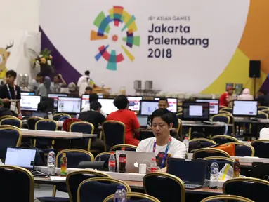 Sejumlah pewarta baik dalam maupun luar negeri beraktivitas di ruang pusat media Asian Games 2018 di JCC, Jakarta, Selasa (14/8). Asian Games 2018 berlangsung hingga 2 September mendatang. (Liputan6.com/Helmi Fithriansyah)