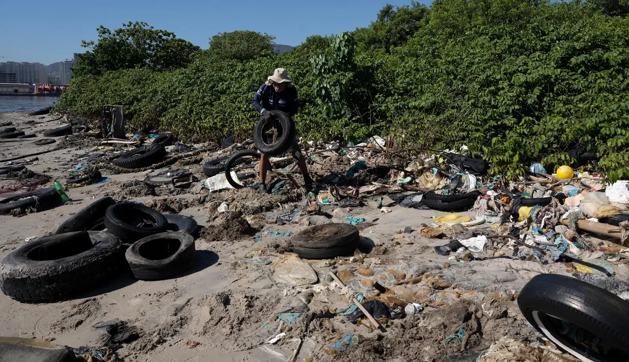 Seorang pria mengumpulkan sampah di pantai Pulau Pombeba, Teluk Guanabara, Rio de Janeiro, Brasil, Senin 17 Februari 2025. (Pablo PORCIUNCULA/AFP)