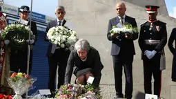 Perdana Menteri Inggris Theresa May menaruh bunga saat upacara peringatan setahun serangan teror Jembatan London, di London Bridge, Inggris (3/6). (AFP/Daniel Leal-Olivas)