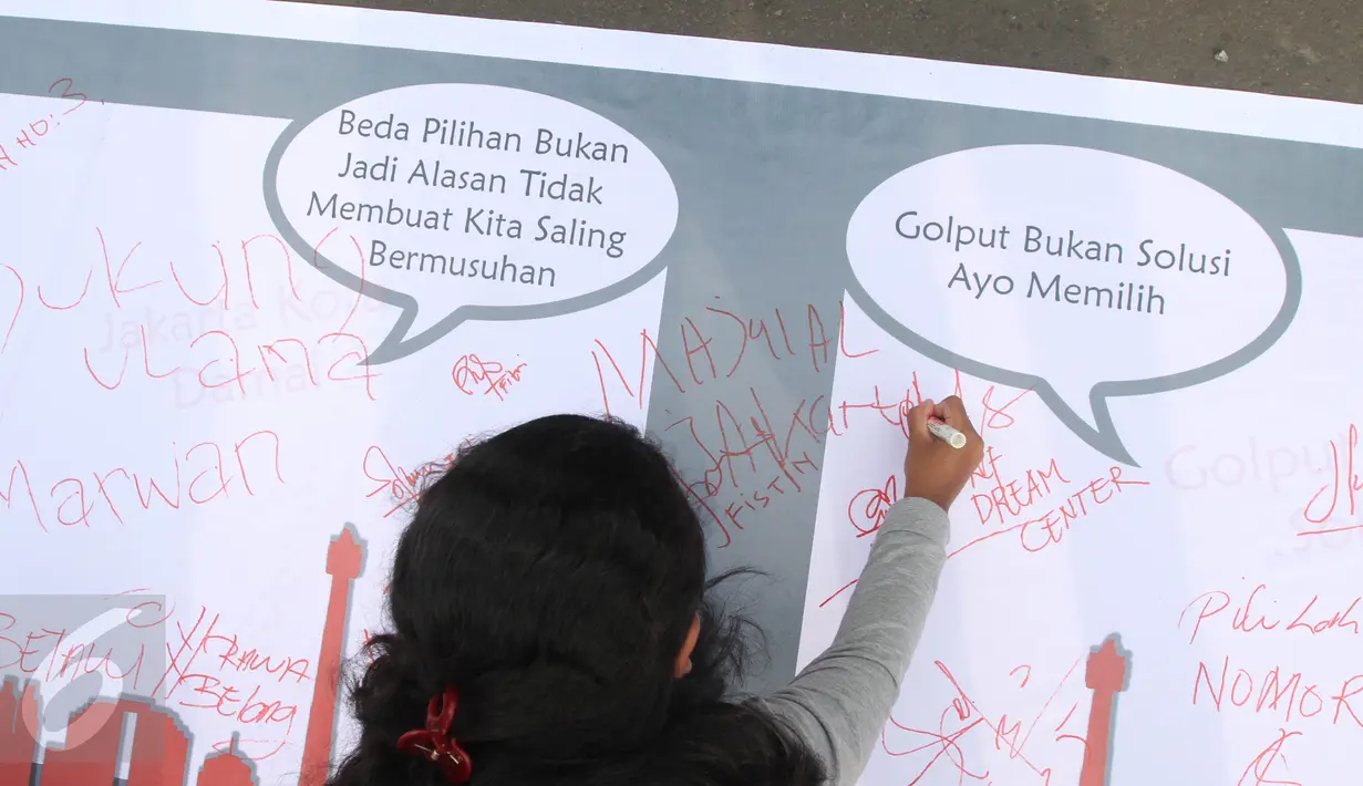 Seorang warga melakukan tanda tangan di bentangan sapanduk panjang di Bundaran HI, Jakarta, Minggu (16/4). Ratusan tanda tangan tersebut di bentuk untuk mendukung pilkada DKI Jakarta yang damai dan tidak golput. (Liputan6.com/Angga Yuniar)
