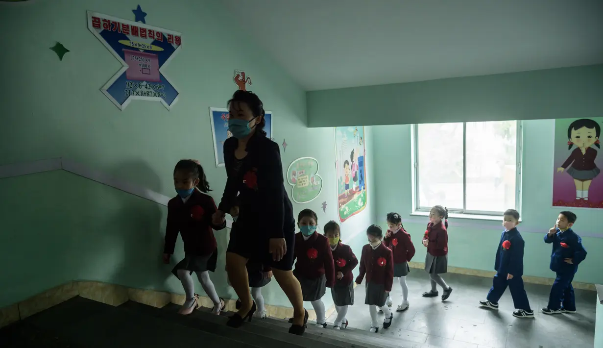 Anak-anak sekolah dasar dengan memakai masker tiba untuk mengikuti kelas di Sekolah Dasar Hasin di Distrik Sosong di Pyongyang, Rabu (3/6/2020). Korea Utara membuka kembali sekolah - sekolah di bulan ini setelah sebelumnya meliburkan karena kekhawatiran penyebaran virus corona. (KIM Won Jin / AFP)