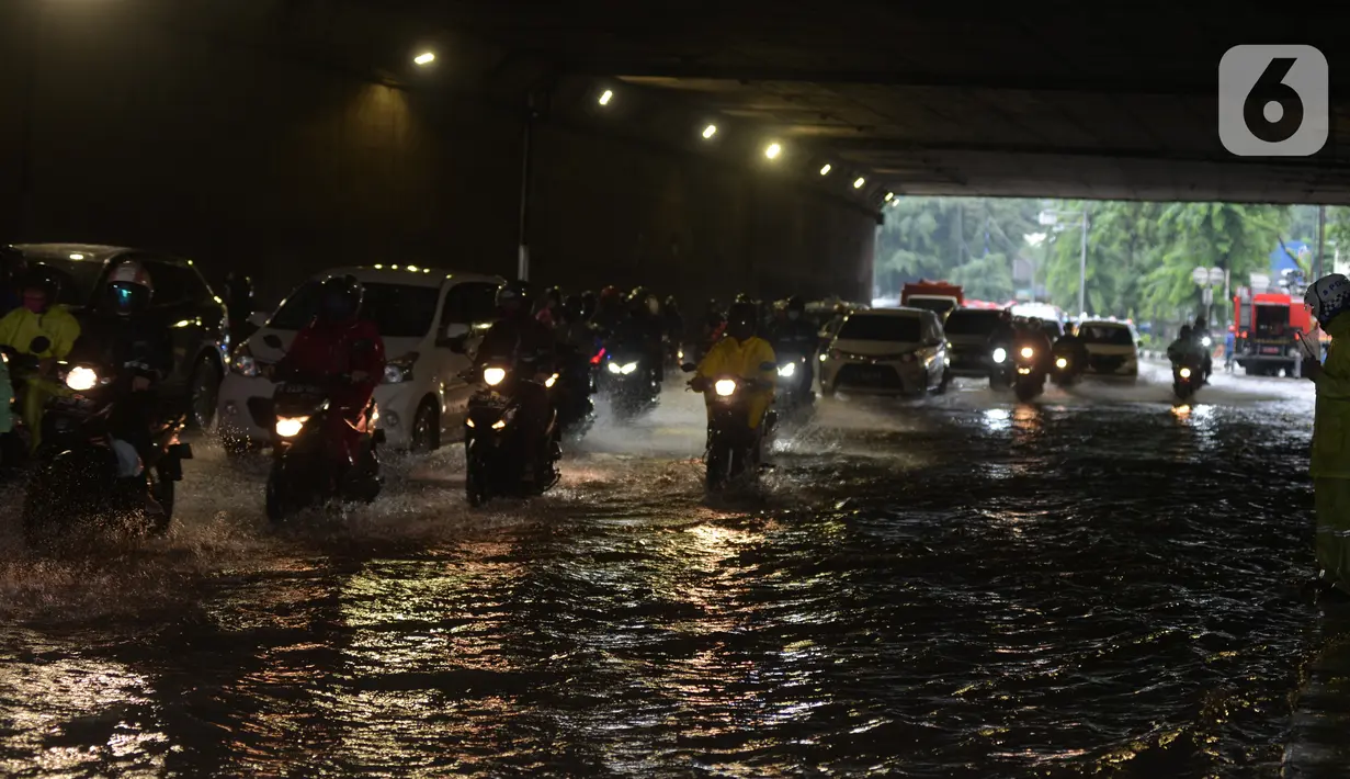 Pengendara sepeda motor menerjang banjir yang merendam terowongan di Cawang, Jakarta, Jumat (19/2/2021). Hujan yang turun sejak semalam membuat sejumlah jalanan di Ibu Kota tergenang banjir dengan ketinggian sekitar 30-50 cm. (merdeka.com/Imam Buhori)