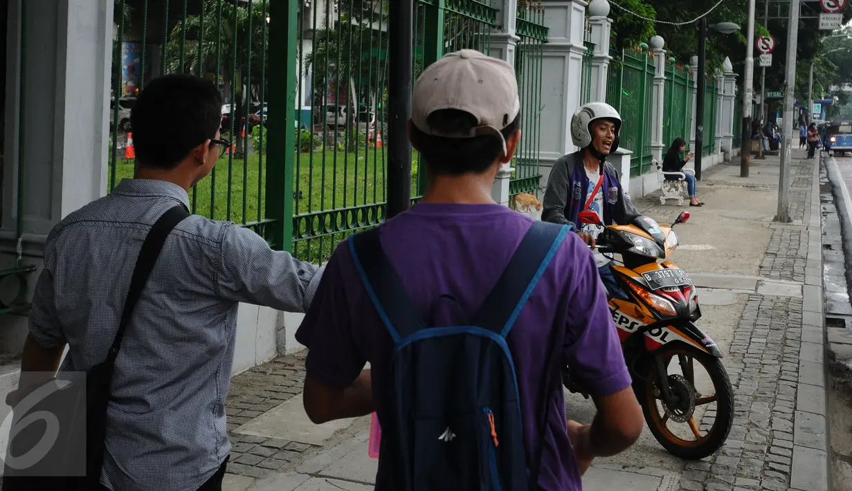 Perwakilan komunitas peduli pejalan kaki menegur pengguna motor yang parkir di trotoar Jalan Medan Merdeka Timur, Jakarta, Jumat (17/3). Mereka menghimbau pengguna motor untuk tidak melewati dan parkir di trotoar jalan. (Liputan6.com/Helmi Fithriansyah)