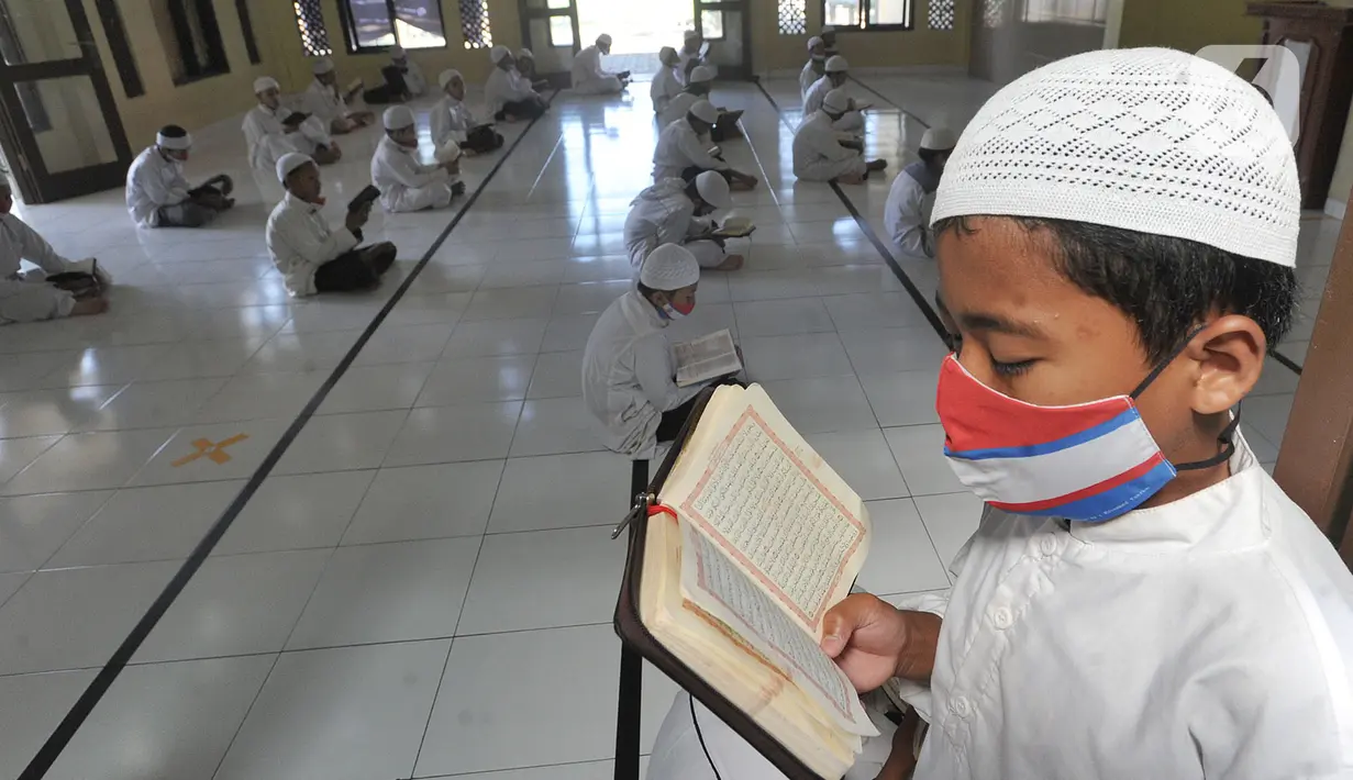 Santri berusia belasan tahun membaca Al quran atau tadarus bersama-sama dengan menerapkan jaga jarak di Masjid Daarul Qu'ran Pesantren Al Kautsar, Cibinong, Bogor, Kamis (7/5/2020). Kegiatan Khatam Al quran tersebut dilakukan rutin di setiap bulan Ramadan. (merdeka.com/Arie Basuki)