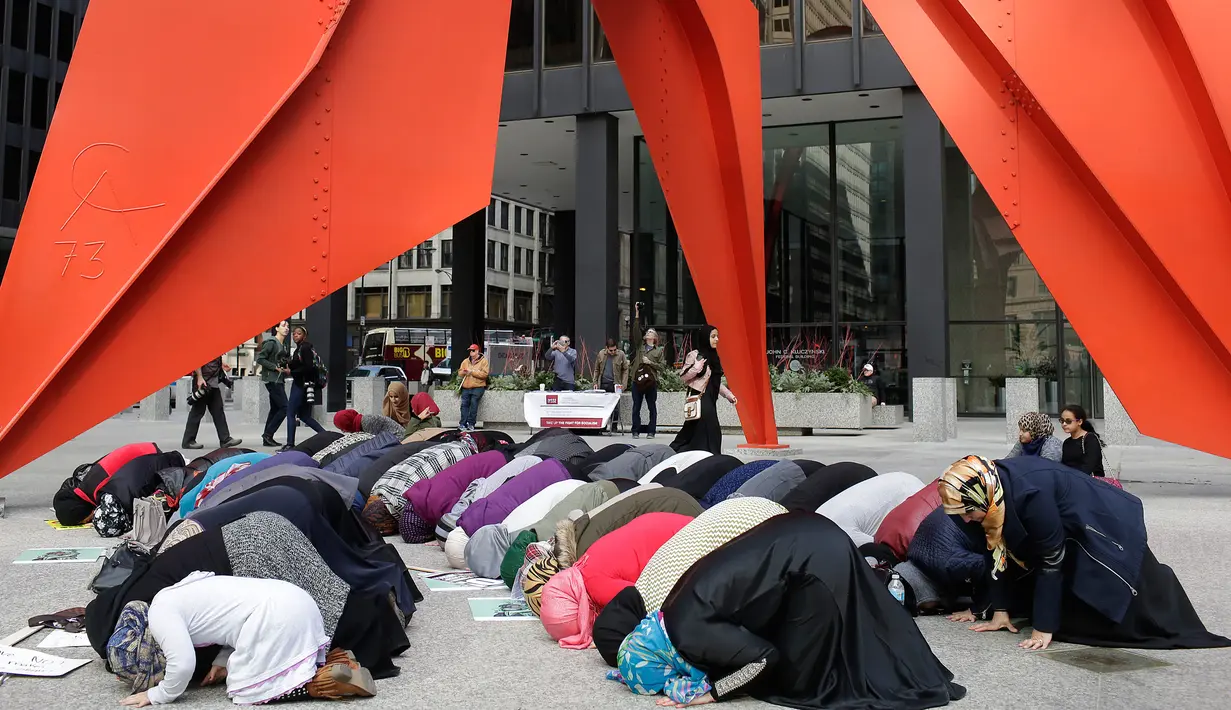Sejumlah perempuan Muslim menunaikan salat disela-sela aksi protes terhadap Presiden AS Donald Trump terkait kebijakan pelarangan sejumlah negara muslim ke AS, di Chicago, Illinois, AS, Minggu (19/2). (AFP PHOTO / Joshua LOTT)
