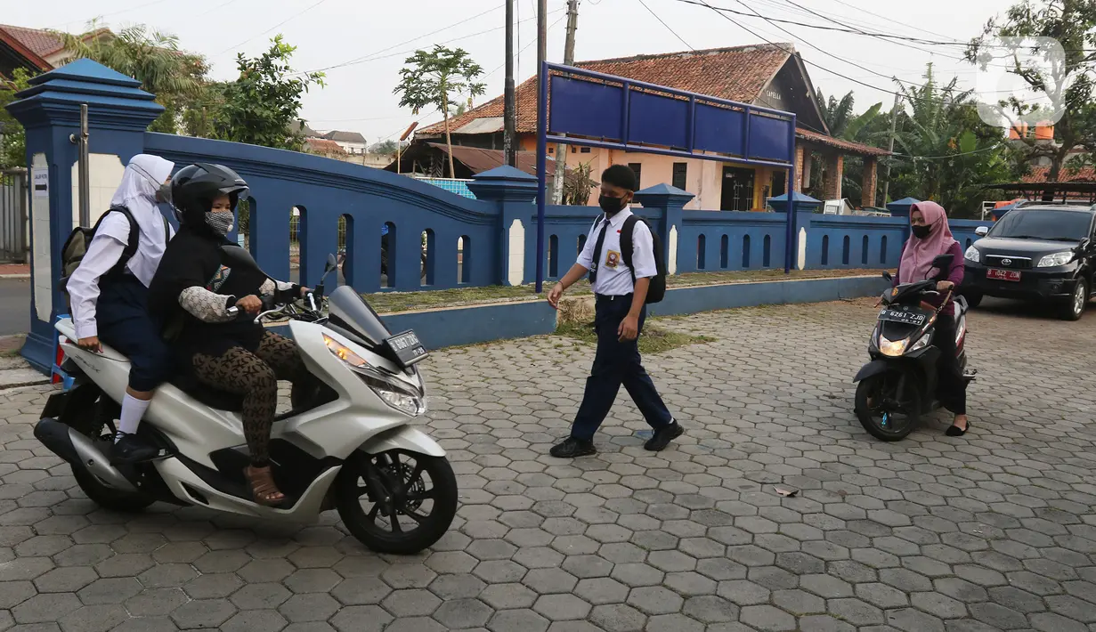 Siswa dan siswi tiba untuk mengikuti Pembelajaran Tatap Muka Terbatas (PTMT) di SMPN 1 Depok, Depok, Jawa Barat, Senin (4/10/2021). PTMT diberlakukan dengan protokol kesehatan dan pembelajaran hanya dilakukan seminggu dua kali selama dua jam. (Liputan6.com/Herman Zakharia)