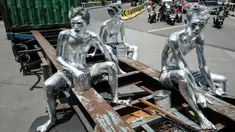 Foto yang diambil pada 7 April 2025 ini menunjukkan manusia silver Keris Munandar (kanan), saudaranya Ari Munandar (kiri), dan tetangganya Riyan Ahmad Fazriyansah menumpang di bagian belakang truk kontainer untuk mencapai persimpangan di Jakarta. (Yasuyoshi CHIBA/AFP)