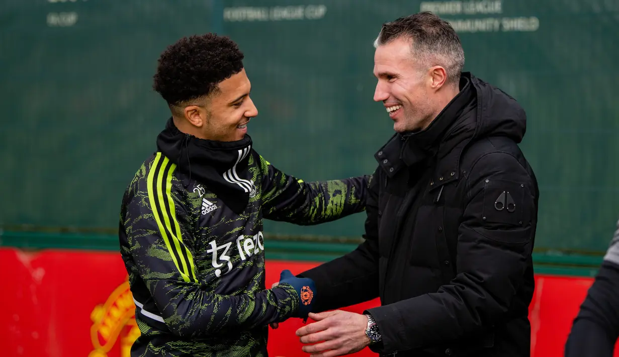 Pemain Manchester United, Jadon Sancho (kiri) bersalaman dengan Robin Van Persie yang merupakan mantan pemain MU saat akan menjalani sesi latihan di Carrington, Rabu (22/2/2023). (Twitter/Manchester United)