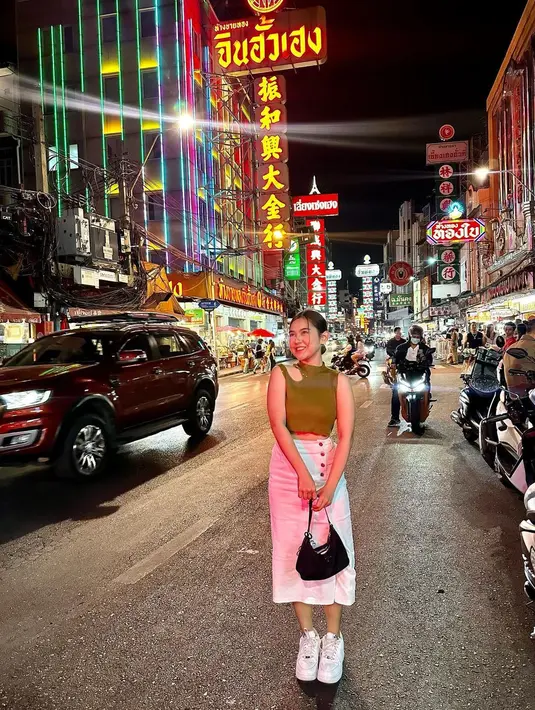 Berpose di China Town, pelantun ‘Terlukis Indah’ itu tampil keren dengan padanan cut out top warna hijau cerah, pencil skirt, sneakers, dan shoulder bag.  [Foto: IG/zivamagnolya].