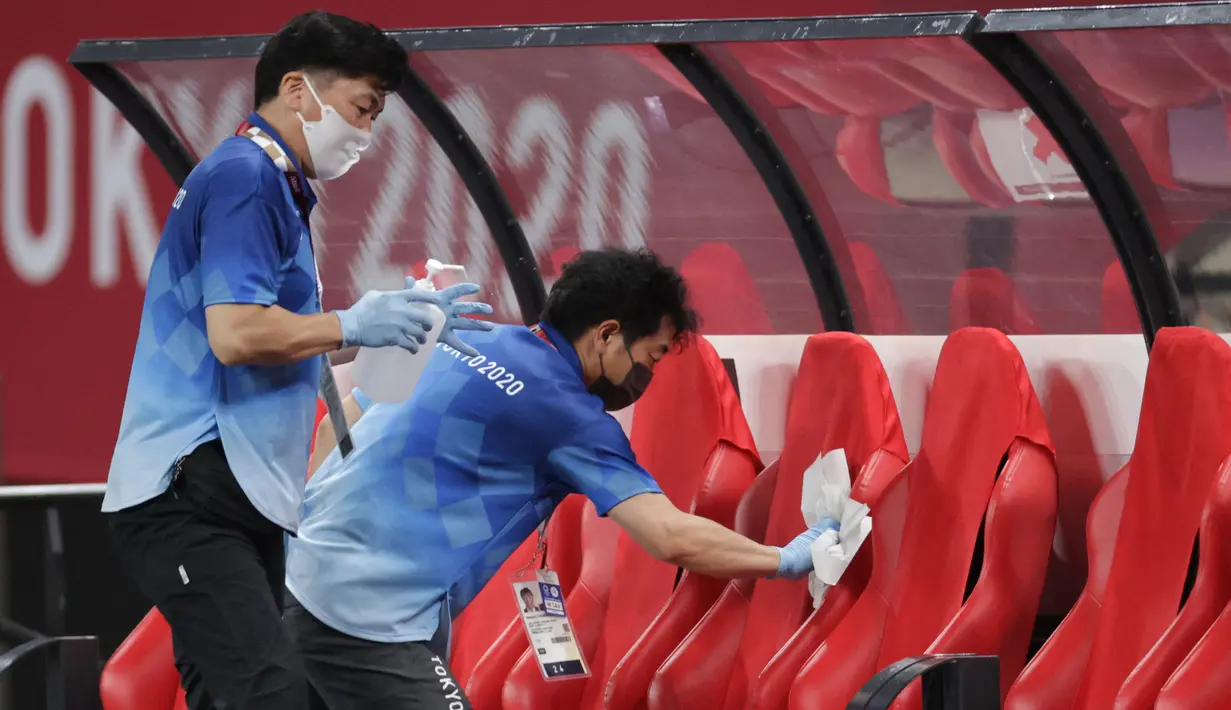 Petugas mendisinfeksi kursi untuk menghentikan penyebaran virus corona COVID-19 setelah pertandingan sepak bola putaran pertama grup C putra Olimpiade Tokyo 2020 antara Mesir dan Spanyol di Sapporo Dome, Sapporo, Jepang, Kamis (22/7/2021). (ASANO IKKO/AFP)