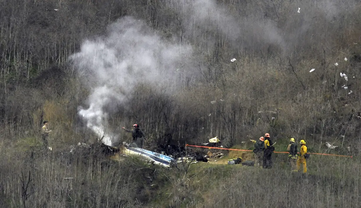 Petugas pemadam kebakaran berusaha memadamkan api di lokasi kecelakaan helikopter yang ditumpangi pebasket NBA Kobe Bryant di Calabasas, California (26/1/2020). Putri Bryant yang berusia 13 tahun, Gianna Bryant juga ikut meninggal dunia dalam insiden tersebut. (AP Photo/Mark J. Terrill)