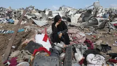Seorang wanita Palestina yang terpaksa mengungsi duduk bersama barang-barangnya setelah serangan Israel di kamp pengungsi Deir el-Balah, Jalur Gaza tengah, pada 21 Agustus 2025. (Eyad BABA/AFP)