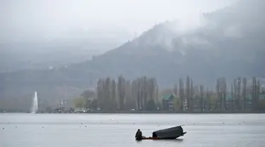 Seorang awak perahu Kashmir mengayuh sebuah perahu saat hujan di Danau Dal di Srinagar (20/3). Danau Dal dijuluki sebagai Jewel in the Crown of Kashmir atau Srinagar Jewel. (AFP Photo/Tauseef Mustafa)