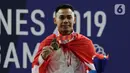 Lifter Eko Yuli menunjukkan medali emas SEA Games 2019 cabang angkat besi nomor 61 kg di Stadion Rizal Memorial, Manila, Filipina, Minggu (1/12/2019). Dirinya meraih emas dengan total angkatan 309 kg. (Bola.com/M Iqbal Ichsan)