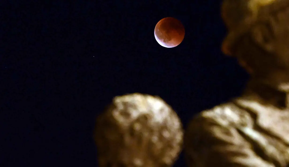 Gerhana bulan kali ini memberikan pemandangan terbaik di wilayah Asia dan Australia bagian barat. Tampak dalam foto, Gerhana Bulan Total yang disertai dengan fenomena Bulan Darah terlihat di atas monumen Gemidzhii di Skopje, Makedonia Utara pada 8 September 2025. (Robert ATANASOVSKI/AFP)