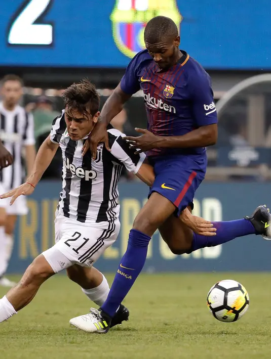 Penyerang Juventus, Paulo Dybala berusaha melewati pemain Barcelona, Nelsinho saat bertanding pada ICC 2017 di Stadion MetLife di East Rutherford, N.J. (22/7). Barcelona menang atas Juventus dengan skor 2-1. (AP Photo / Julio Cortez)