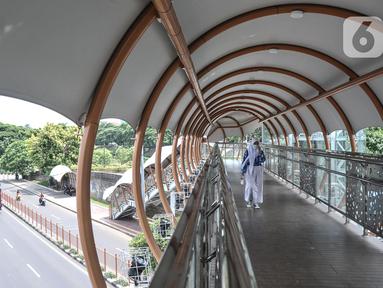 Pejalan kaki menggunakan fasilitas jembatan penyeberangan orang (JPO) di Jalan Kolonel Sugiono, Duren Sawit, Jakarta Timur, Senin (7/2/2022). JPO Kolonel Sugiono yang berada dekat Kanal Banjir Timur itu didesain dengan bentuk yang modern namun sarat kearifan lokal. (merdeka.com/Iqbal S Nugroho)