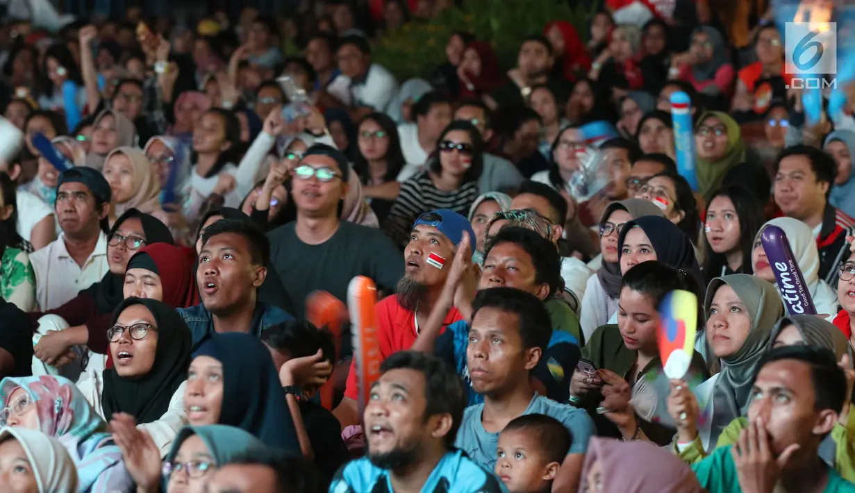Suporter tim bulutangkis Indonesia terlihat tegang saat menyaksikan siaran langsung laga perempat final dan 16 besar bulutangkis Asian Games 2018 melalui layar lebar di kawasan kompleks GBK, Jakarta, Sabtu (25/8). (Liputan6.com/Helmi Fithriansyah)