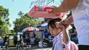 Seorang pria menggunakan tas sekolah untuk melindungi seorang anak dari sengatan matahari saat mereka meninggalkan sekolah di Manila, Filipina pada Senin 3 Maret 2025. (Jam STA ROSA/AFP)