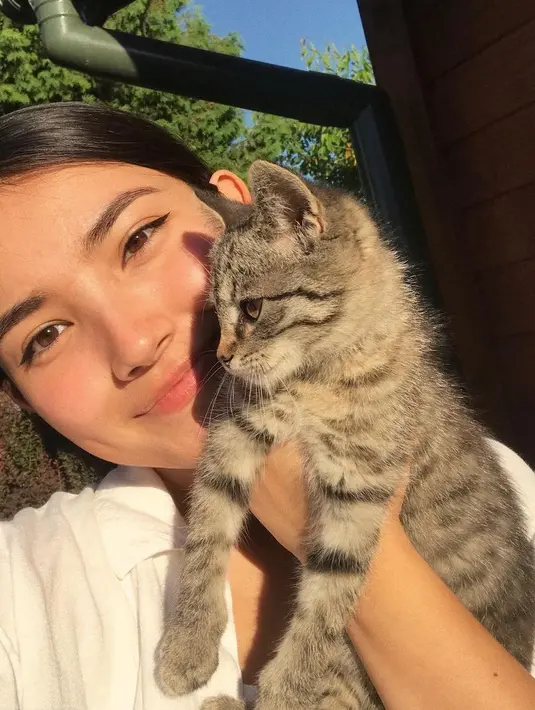 Maria Zhang berpose bersama kucingnya. Menggemaskan, Maria memamerkan kulit glowingnya di bawah sinar matahari, dengan sentuhan winged-eyeliner tipis. [Foto: Instagram/mariaxzhang]