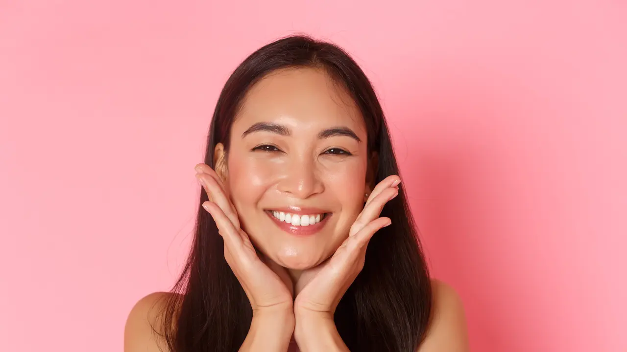 Seorang perempuan tersenyum sambil memegang kedua pipinya (Foto Dok: Freepik/benzoix)
