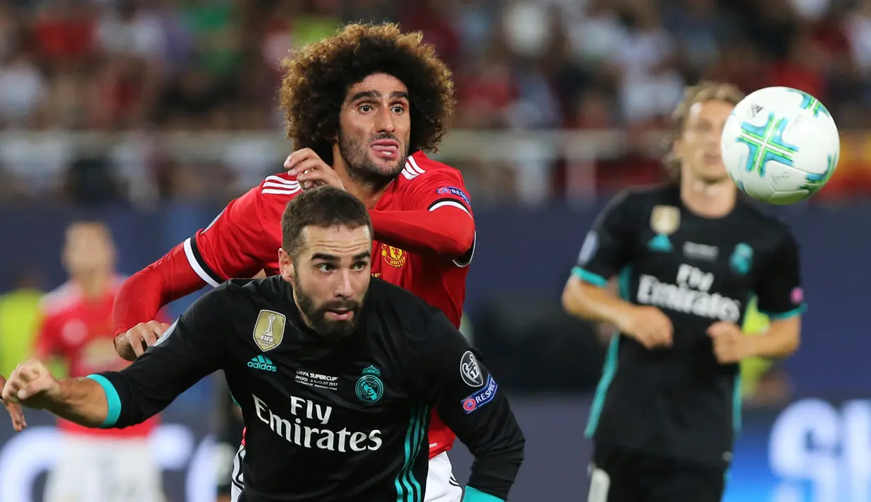 Gelandang Manchester United (MU), Marouane Fellaini berusaha merebut bola dari pemain Real Madrid, Daniel Carvajal pada Piala Super Eropa di Macedonia, Selasa (8/8). Madrid keluar sebagai juara usai menundukkan MU dengan skor 2-1. (AP/Boris Grdanoski)
